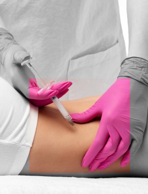 Estetik kozmetik uzmanı bir kadının vücudunda yağ yakmak için lipolitik enjeksiyon yapar. Güzellik salonunda kadın estetiği. Kozmetoloji konsepti..