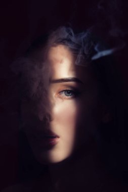 Güzel makyajlı, dolgun dudaklı bir kadın sigarasını yakın plan içer..