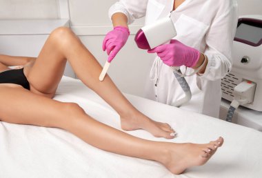 Bir kadının vücudunda tüy çıkarma prosedürü. Güzellik uzmanı bir güzellik salonunda lazer gençleştirme yapıyor. İstenmeyen vücut kılları alınıyor. Donanım ipl kozmetolojisi