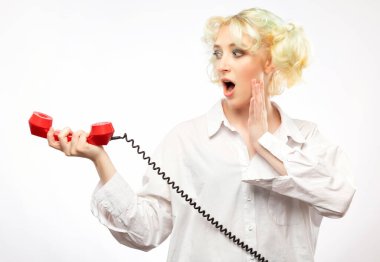Beyaz tişörtlü, kıvırcık saçlı, eski bir telefondan konuşan güzel sarışın kız.
