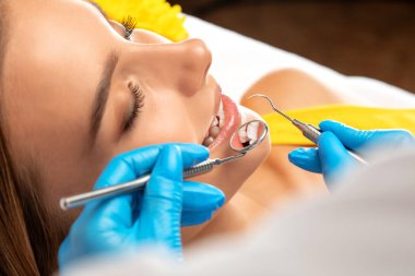 Diş hekimi, dişçi kliniğinde genç ve güzel bir kadının dişlerini tedavi eder. Diş dolgusu.