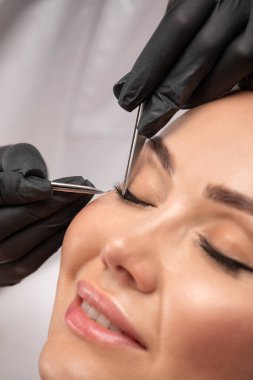 Güzellik salonunda uzun kirpikleri olan güzel bir kadın. Kirpik uzatma prosedürü. Kırbaçlar yakın.