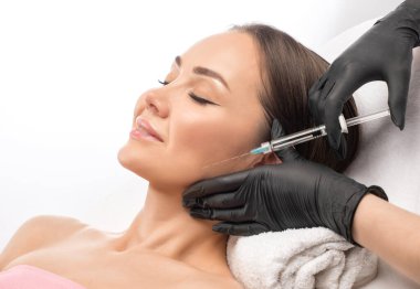 Kozmetik uzmanı güzel bir kadının yüzüne kırışıklık önleyici iğneler yapıyor. Güzellik salonunda kadın estetiği..