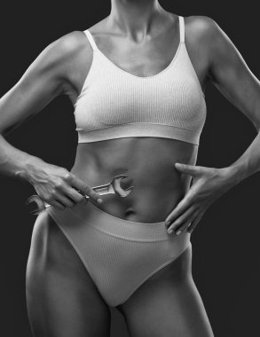 İnce, güzel bir kadın karnının yanında İngiliz anahtarı tutuyor..