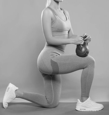 Sıska, leylak eşofmanlı vücut geliştiren kız, ağır bir ağırlık kaldırıyor, kardiyo çalışması yapıyor. Spor konsepti, yağ yakma ve sağlıklı yaşam tarzı..