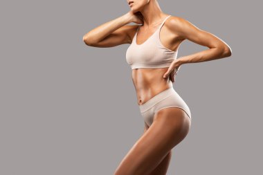 Siyah arka planda bej iç çamaşırlı ince esmer bir kadın. Sağlıklı yaşam tarzı, spor ve diyet.
