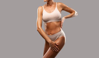 Siyah arka planda bej iç çamaşırlı ince esmer bir kadın. Sağlıklı yaşam tarzı, spor ve diyet.