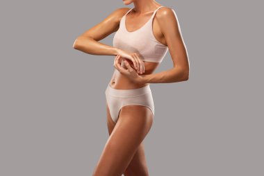 Siyah arka planda bej iç çamaşırlı ince esmer bir kadın. Sağlıklı yaşam tarzı, spor ve diyet.