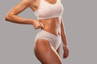 Siyah arka planda bej iç çamaşırlı ince esmer bir kadın. Sağlıklı yaşam tarzı, spor ve diyet.