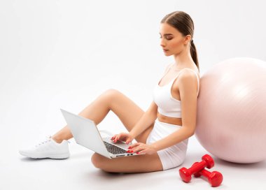 Beyaz eşofmanlı, ince esmer kadın blogcu beyaz bir arka plana karşı. Sağlıklı yaşam tarzı, spor ve diyet.