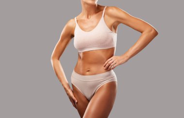 Siyah arka planda bej iç çamaşırlı ince esmer bir kadın. Sağlıklı yaşam tarzı, spor ve diyet.