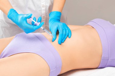 Bir kadının vücudunda yağ yakmak için lipotik enjeksiyon. Güzellik salonunda kadın estetiği. Kozmetoloji konsepti..