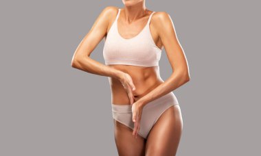 Siyah arka planda bej iç çamaşırlı ince esmer bir kadın. Sağlıklı yaşam tarzı, spor ve diyet.