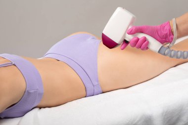 Bir kadının vücudunda epilasyon tüy çıkarma prosedürü. Güzellik uzmanı bir güzellik salonunda lazer gençleştirme yapıyor. İstenmeyen vücut kılları alınıyor. 