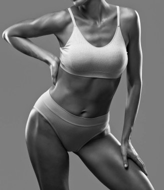 Siyah arka planda bej iç çamaşırlı ince esmer bir kadın. Sağlıklı yaşam tarzı, spor ve diyet.
