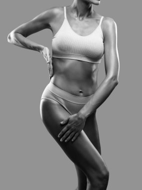 Siyah arka planda bej iç çamaşırlı ince esmer bir kadın. Sağlıklı yaşam tarzı, spor ve diyet.