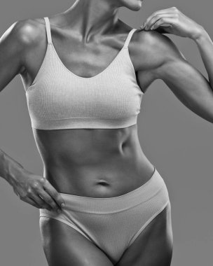 Siyah arka planda bej iç çamaşırlı ince esmer bir kadın. Sağlıklı yaşam tarzı, spor ve diyet.