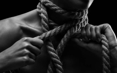 Genç bir kadın vücudundan ve boynundan ip koparıyor. Siyah beyaz fotoğraf.