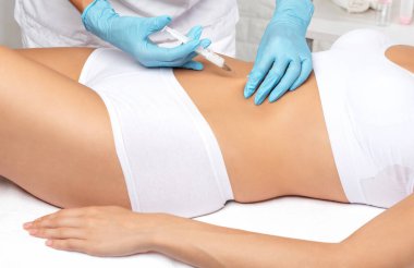 Bir kadının vücudunda yağ yakmak için lipotik enjeksiyon. Güzellik salonunda kadın estetiği. Kozmetoloji konsepti..