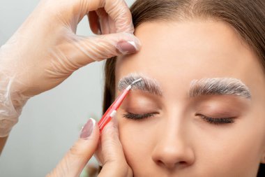Makyaj sanatçısı kaşların uzun süreli stilini yapar ve kaşlarını boyar. Kaş kaplaması. Profesyonel makyaj ve yüz bakımı..