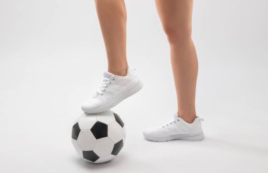 Beyaz takım elbiseli, beyaz arka planda siyah beyaz futbol topu olan güzel seksi kız..