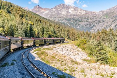 Skagway, AK - 7 Eylül 2022 Beyaz Geçit ve Yukon Rotası treni Skagway 'in doğusundaki dağların arasından geçiyor..