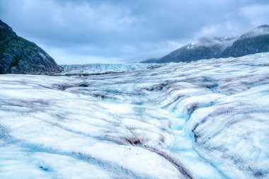 Alaska 'daki Mendenhall Buzulu' ndaki eriyen buzullar kristal berrak mavi sudan oluşan dolambaçlı bir dere oluşturur.