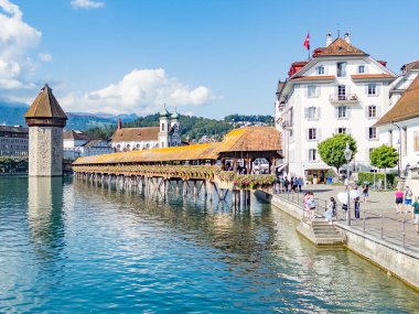Lucerne, İsviçre - 16 Ağustos 2024: Turistler Reuss Nehri kıyısındaki tarihi ahşap Şapel Köprüsü veya Kapellbrucke 'yi ziyaret ettiler