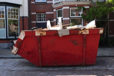 İnşaat alanının yakınındaki turuncu çöp konteynırı, ev yenileme ya da bakım