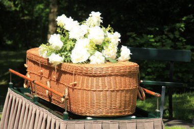 A willow casket - Environmentally Friendly and contemporary style - on a catafalque during an outdoor ceremony clipart
