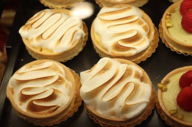 Bir dükkanın vitrininde kremalı pasta, yumurtanın beyazına dayalı küçük bir Fransız pastası.