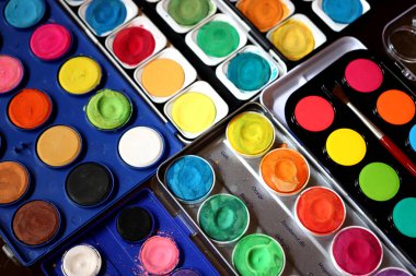 Different used boxes of waterpaint in a studio clipart