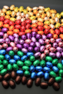 Bir grup folyo sarılıp gökkuşağı renklerine bürünmüş çikolatalı yumurta.