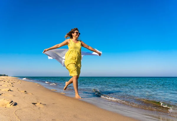 晴れたビーチを歩いているショールを保持する幸せな美しい女性 — ストック写真