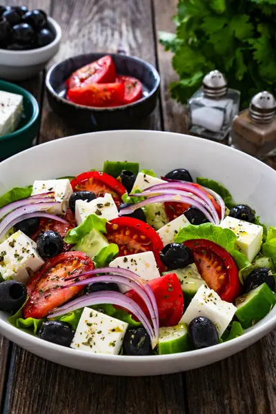 Greek style salad - fresh vegetables with feta cheese on wooden table