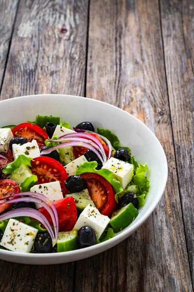 Greek style salad - fresh vegetables with feta cheese on wooden table
