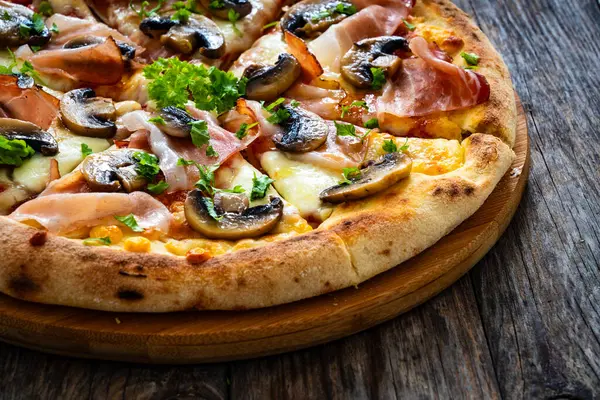 在木制桌子上放有火腿 莫扎拉奶酪和白蘑菇的比萨斑点 — 图库照片