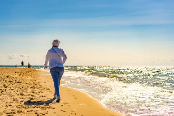晴れたビーチを歩く美しい中間の大人の女性 — ストック写真