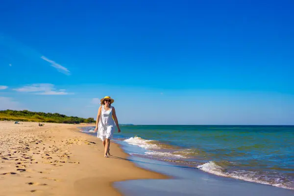 stock image Beautiful mid adult woman walking on sunny beach 