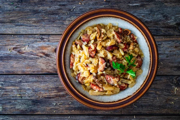 Cooked cabbage with sliced sausage on wooden table