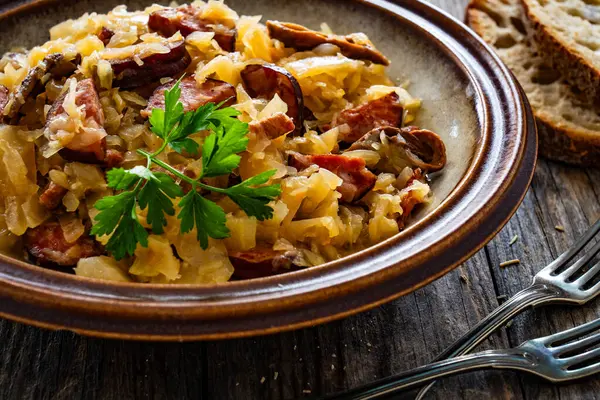 Cooked cabbage with sliced sausage on wooden table