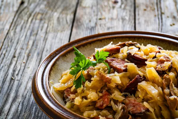 Cooked cabbage with sliced sausage on wooden table