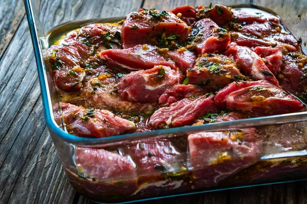 在木制桌子上的耐热盘子中 用生菜腌制的猪肉面颊 — 图库照片