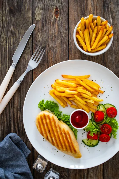 木のテーブルにフライドポテトと新鮮な野菜をグリルチキン胸 — ストック写真