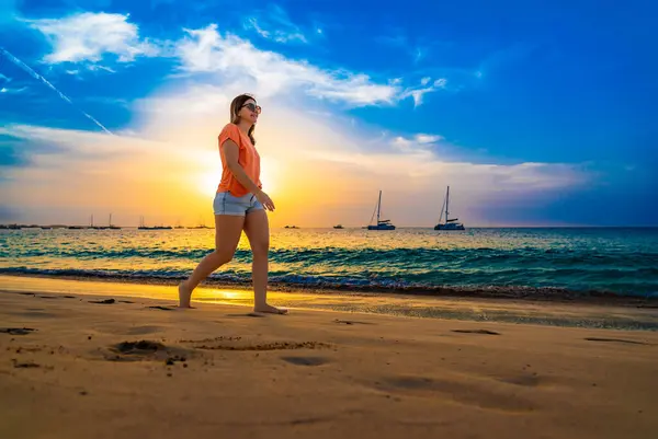 日当たりの良いビーチを歩く美しい中年の女性 — ストック写真