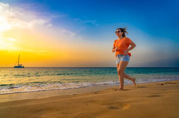 晴れたビーチで走っている美しい中年の女性 — ストック写真