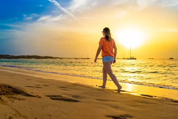 日当たりの良いビーチを歩く美しい中年の女性 — ストック写真