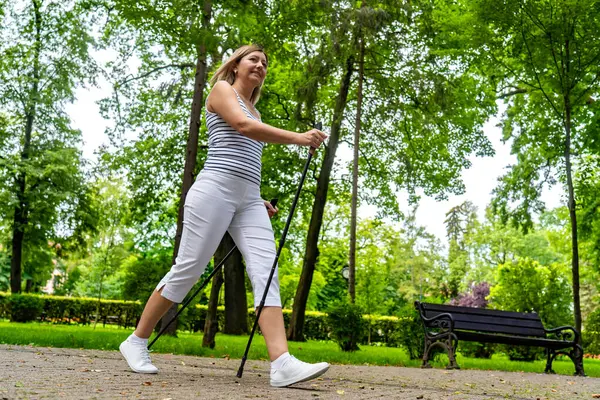 ノルディックウォーキング 都市公園で運動している女性 — ストック写真