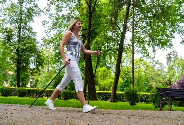 ノルディックウォーキング 都市公園で運動している女性 — ストック写真