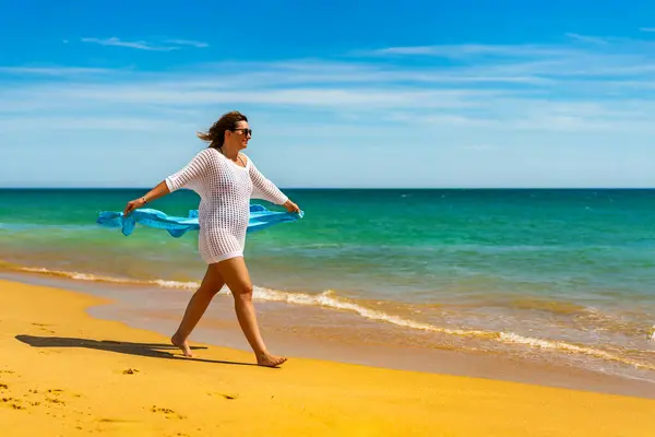 ショールを保持する晴れたビーチで歩く美しい女性 — ストック写真